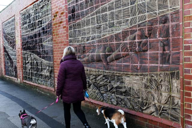 A woman walks past the walled sculptures in Featherstone