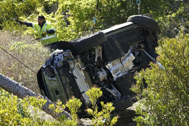 Workers move a vehicle on its side after a rollover accident involving golfer Tiger Woods Tuesday, Feb. 23, 2021, in Rancho Palos Verdes, Calif., a suburb of Los Angeles. Woods suffered leg injuries in the one-car accident and was undergoing surgery, authorities and his manager said. (AP Photo/Marcio Jose Sanchez)