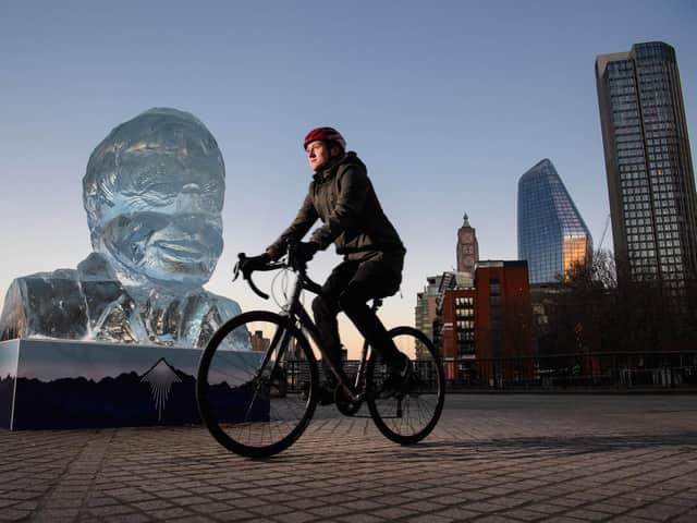 Library image of a cyclist riding past an ice-sculpture of Sir David Attenborough