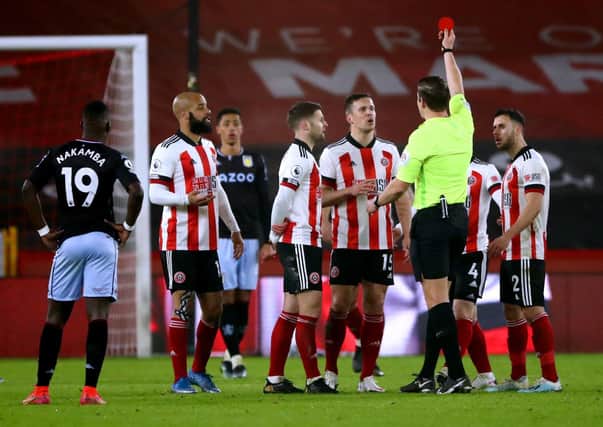 Sheffield United's Phil Jagielka (centre right) sees his yellow card upgraded to a red card after referee Robert Jones consults the VAR. Picture: PA