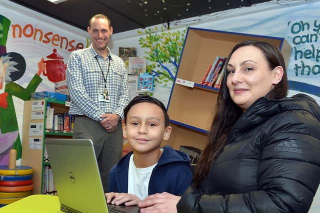 Athelstan Primary School assistant headteacher James Mills with Castro Hart-Richards and Vikki Hart with a device donated by Laptops for Kids in Sheffield.