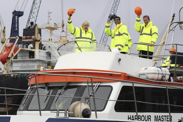 Boris Johnson (L) and Chancellor of the Exchequer Rishi Sunak (C), stand on board a boat on the River Tees on March 4, 2021 in Teesport, England. Teesport has been chosen as one of eight sites for new Freeports .