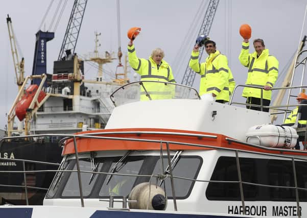 Prime Minister Boris Johnson (L) and Chancellor of the Exchequer Rishi Sunak (C), stand on board a boat on the River Tees on March 4, 2021 in Teesport, England. Teesport has been chosen as one of eight sites for new Freeports.
