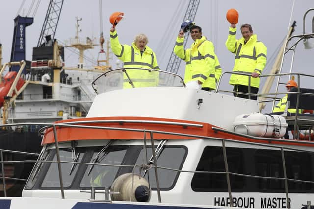 Boris Johnson (L) and Chancellor of the Exchequer Rishi Sunak (C), stand on board a boat on the River Tees on March 4, 2021 in Teesport, England. Teesport has been chosen as one of eight sites for new Freeports.