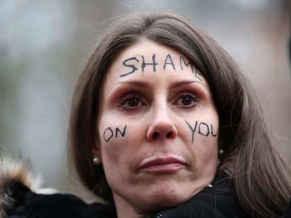 A woman with the words 'Shame on you' written on her face stands outside New Scotland Yard in London. Picture: Yui Mok