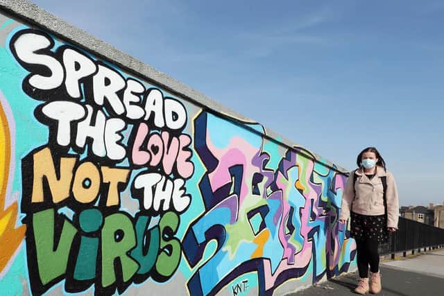A woman walks past street art that reads "Spread the love not the virus" in Hull during England's third national lockdown to curb the spread of coronavirus.