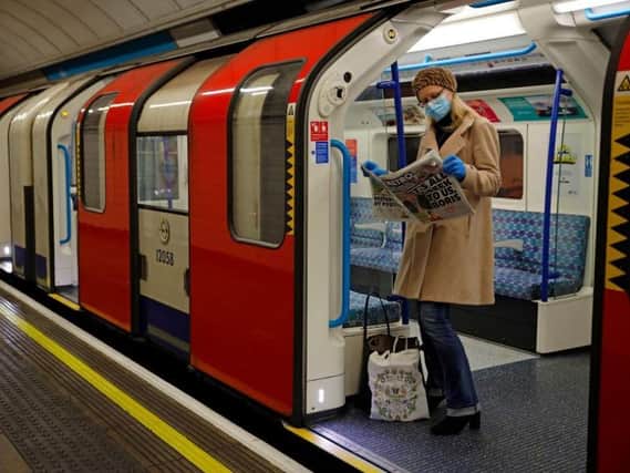 A woman reads a newspaper on the London Underground. Photo by TOLGA AKMEN/AFP via Getty Images.