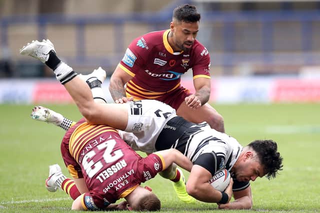 Hull FC's Andre Savelio is tackled by Huddersfield Giants' Oliver Rusell.