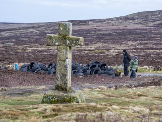 Dog walkers examine the pile of tyres dumped on Ilkley Moor