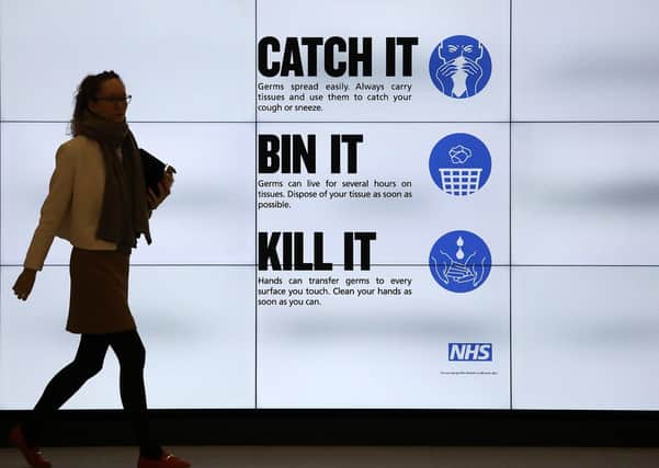 An NHS catch it, bin it, kill it sign on TV screens in the entrance to the QEII Centre in London.