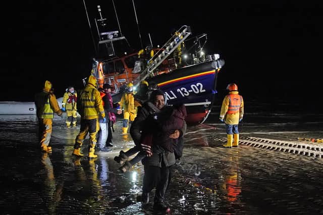A lady carries a small child as a group of people thought to be migrants are brought in to Dungeness, Kent, after being rescued by the RNLI following a small boat incident in the Channel at the weekend.
