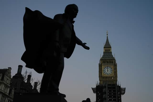 The sun sets over the Houses of Parliament and statue of David Lloyd George in Parliament Square, London