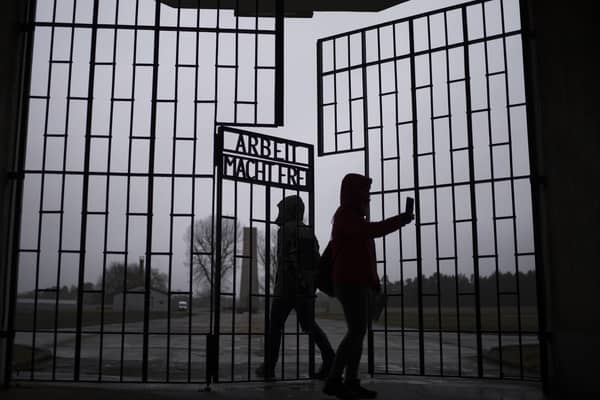 People take photos as they enter the Sachsenhausen Nazi death camp through the gate with the phrase 'Arbeit macht frei' (work sets you free), in Oranienburg, about 30 kilometers (18 miles) north of Berlin ahead of Holocaust Memorial Day.