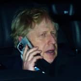 Prime Minister Boris Johnson rides in the back seat of a government car while speaking on a mobile phone as he returns to Downing Street, London (PA)