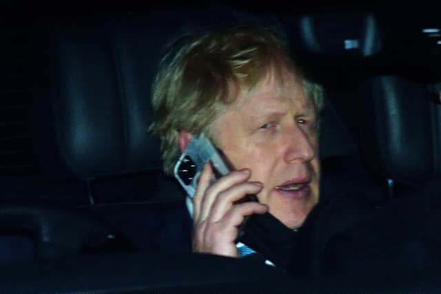 Prime Minister Boris Johnson rides in the back seat of a government car while speaking on a mobile phone as he returns to Downing Street, London (PA)