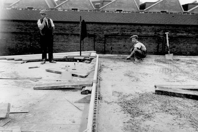 Two workmen laying concrete suface to new bus station in July 1938.