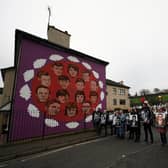 Family members holding photographs of the victims stop at a mural during a remembrance walk to mark the 50th anniversary of Bloody Sunday