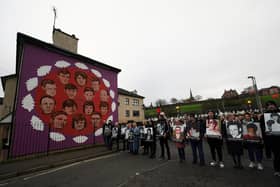 Family members holding photographs of the victims stop at a mural during a remembrance walk to mark the 50th anniversary of Bloody Sunday