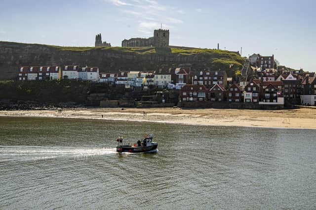 A fishing boat returns back to Whitby harbour in fine weather.