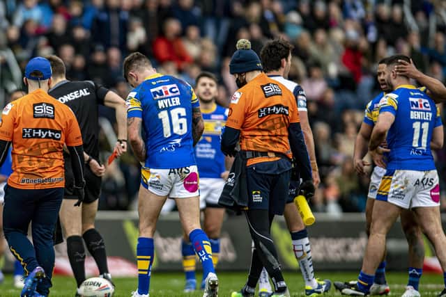 Referee Chris Kendall shows the red card to Rhinos James Bentley, right, on Saturday as Richie Myler hobbles off the park injured.  (Picture: Tony Johnson)