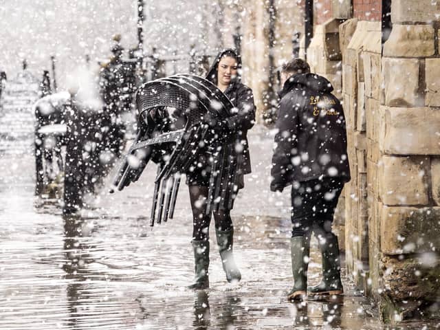 Pub staff move chairs through flood water in heavy snow in York.