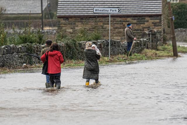 A young family with a baby splash through the flood water on Granny Lane at Mirfield as the River Calder burst its banks during Storm Franklin.