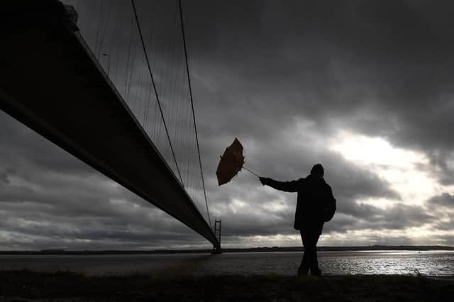 A man struggles to hold onto his umbrella under the Humber Bridge, as Storm Eunice arrives  Picture: Simon Hulme