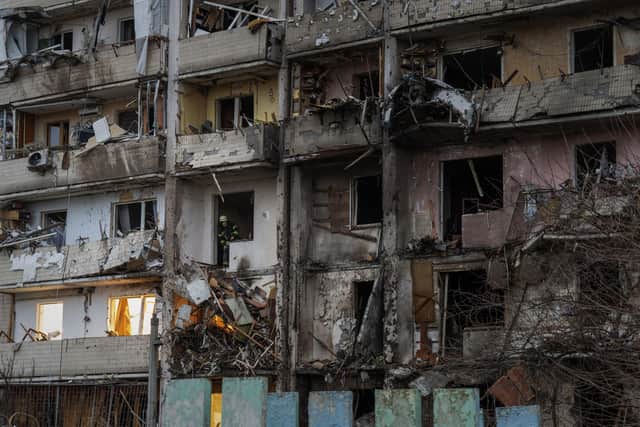 A fire-fighter inspects the damage at a building following a rocket attack on the city of Kyiv, Ukraine, Friday, Feb. 25, 2022.
