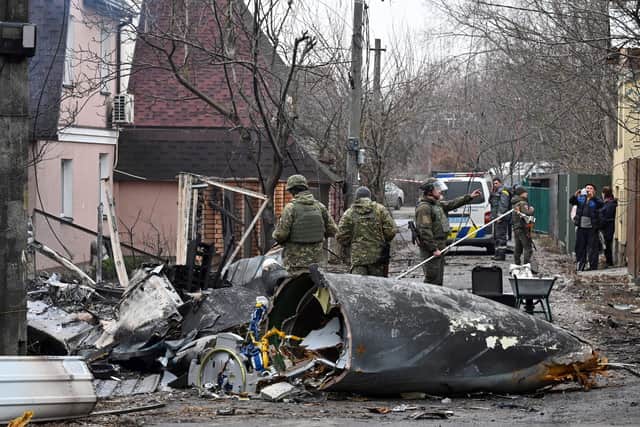Ukrainian servicemen work by the wreckage of an unidentified aircraft which crashed into a private house in a residential area in Kyiv on February 25, 2022. (Photo by GENYA SAVILOV/AFP via Getty Images)