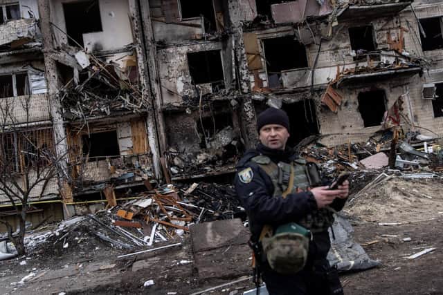 A Ukrainian police officer stands in front of a damaged residential block hit by an early morning missile strike on February 25, 2022 in Kyiv, Ukraine. (Photo by Chris McGrath/Getty Images)