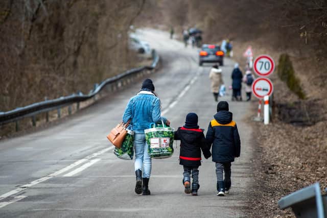 A woman with two children and carrying bags walk on a street to leave Ukraine after crossing the Slovak-Ukrainian border in Ubla, eastern Slovakia, close to the Ukrainian city of Welykyj Beresnyj, on February 25, 2022, following Russia's invasion of the Ukraine. (Photo by PETER LAZAR / AFP)