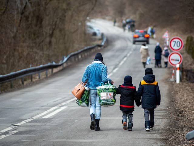 A woman with two children and carrying bags walk on a street to leave Ukraine after crossing the Slovak-Ukrainian border in Ubla, eastern Slovakia, close to the Ukrainian city of Welykyj Beresnyj, on February 25, 2022, following Russia's invasion of the Ukraine. (Photo by PETER LAZAR / AFP)
