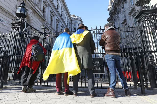 Members of the public wear a Ukrainian flag outside 10 Downing Street in London, following the Russian invasion of Ukraine.