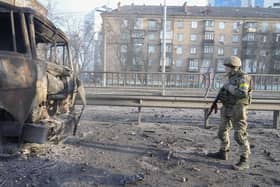 A Ukrainian soldier walks past debris of a burning military truck, on a street in Kyiv, Ukraine.