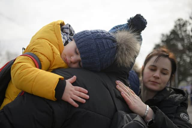 A man hugs his twin boys after they fled the conflict from neighbouring Ukraine at the Romanian-Ukrainian border, in Siret, Romania, Sunday, Feb. 27, 2022.