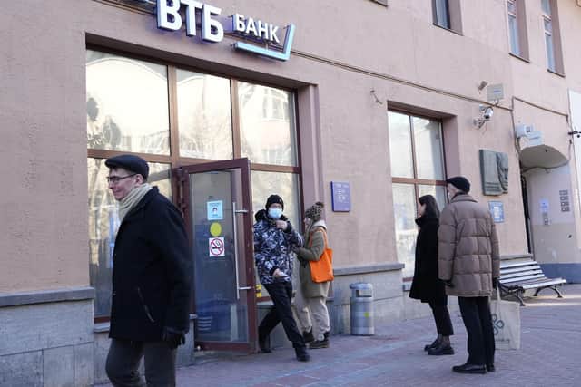People stand in line to withdraw money from an ATM of VTB Bank in downtown Moscow, Russia, Monday, Feb. 28, 2022. Ordinary Russians faced the prospect of higher prices and crimped foreign travel as Western sanctions over the invasion of Ukraine sent the ruble plummeting, leading uneasy people to line up at banks and ATMs on Monday in a country that has seen more than one currency disaster in the post-Soviet era. (AP Photo/Pavel Golovkin).