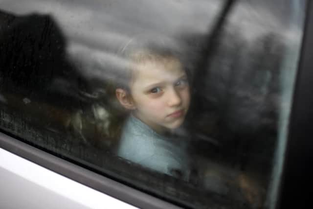 A Ukrainian child looks through the window of a car stuck in traffic, as her family drives towards the Medyka-Shehyni border crossing between Ukraine and Poland. (Photo by DANIEL LEAL/AFP via Getty Images)