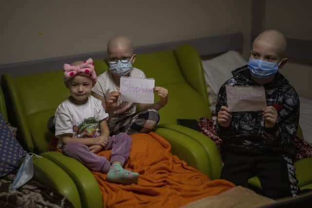 Oncology patients hold up sheets of paper with the words "Stop War" at a basement used as a bomb shelter at the Okhmadet children's hospital in central Kyiv, Ukraine, Monday, Feb. 28, 2022. (AP Photo/Emilio Morenatti).