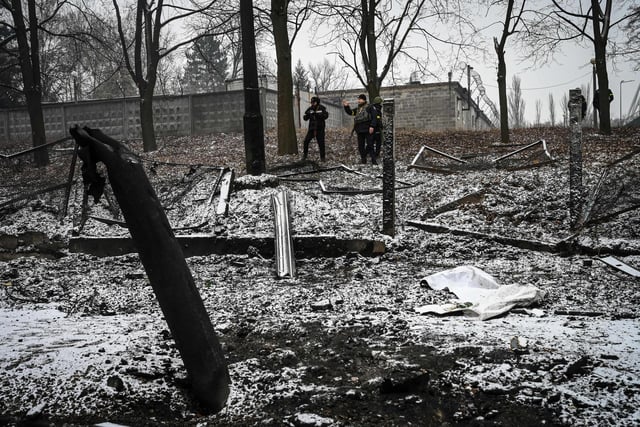 Police officers pass by wreckage of a building after reported shelling in Kyiv on March 2, 2022