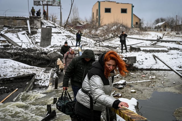 Civilians cross a river on a blown up bridge on Kyivs northern front on March 1, 2022
