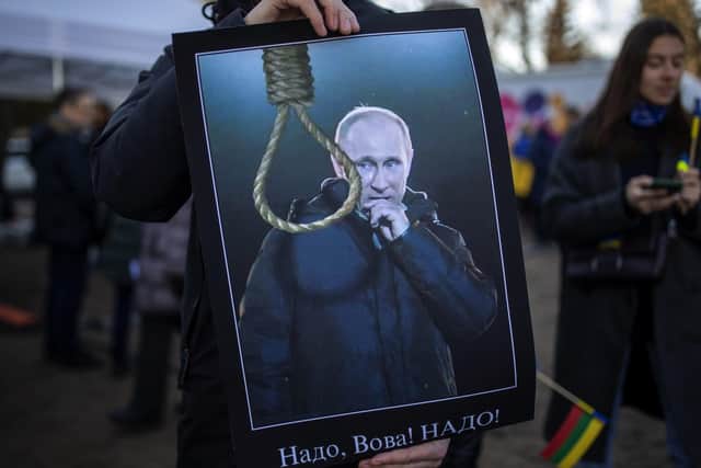 A demonstrator holds a placard depicting a Russia's President Vladimyr Putin as he attends a protest against the Russian invasion of Ukraine in front of the Russian embassy in Vilnius, Lithuania. (AP Photo/Mindaugas Kulbis).