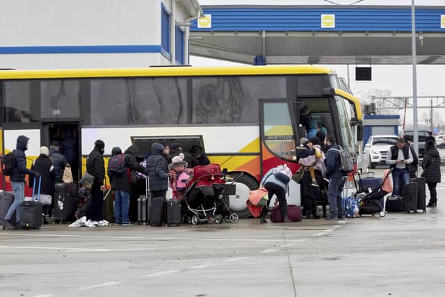 Refugees fleeing war in Ukraine board a bus as they arrive to Palanca, Moldova, Tuesday, March 1, 2022. (AP Photo/Aurel Obreja).