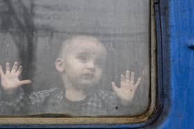 A child watches from from a train carriage waiting to leave Ukraine for western Ukraine at the railway station in Kramatorsk, eastern Ukraine, Sunday, Feb. 27, 2022. The U.N. refugee agency says nearly 120,000 people have so far fled Ukraine into neighboring countries in the wake of the Russian invasion. The number was going up fast as Ukrainians grabbed their belongings and rushed to escape from a deadly Russian onslaught. (AP Photo/Andriy Andriyenko),