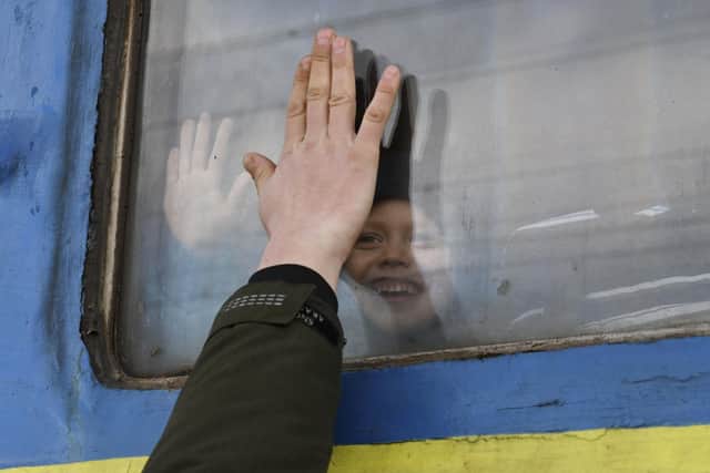A child says goodbye to a relative looking out the window of a train carriage waiting to leave Ukraine for western Ukraine at the railway station in Kramatorsk, eastern Ukraine, Sunday, Feb. 27, 2022. The U.N. refugee agency says nearly 120,000 people have so far fled Ukraine into neighboring countries in the wake of the Russian invasion. The number was going up fast as Ukrainians grabbed their belongings and rushed to escape from a deadly Russian onslaught. (AP Photo/Andriy Andriyenko).