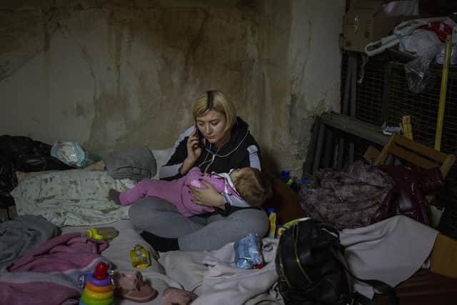 A woman speaks by phone holding her sick baby at a basement used as a bomb shelter at the Okhmadet children's hospital in central Kyiv, Ukraine, Tuesday, March 1. 2022. Russian strikes pounded the central square in Ukraine???s second-largest city and other civilian targets, and a 40-mile convoy of tanks and other vehicles threatened the capital. (AP Photo/Emilio Morenatti).