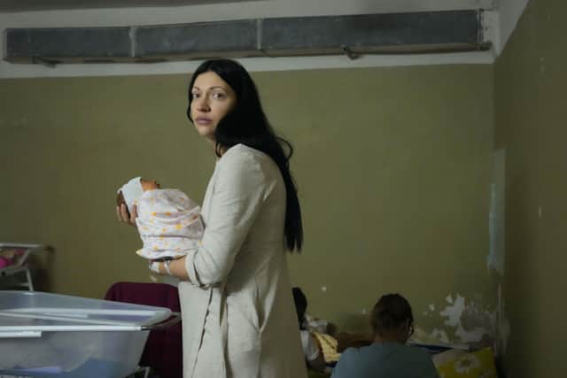 A woman holds her newborn child in the basement of a maternity hospital converted into a medical ward and used as a bomb shelter during an air raid alert, in Kyiv, Ukraine, Wednesday, March 2, 2022. Russian forces have escalated their attacks on crowded cities in what Ukraine's leader called a blatant campaign of terror. (AP Photo/Efrem Lukatsky).