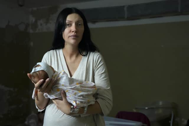 A woman, who did not want to be identified, poses for a photograph as she holds her newborn girl in the basement of a maternity hospital converted into a medical ward and used as a bomb shelter during air raid alerts, in Kyiv, Ukraine, Wednesday, March 2, 2022. Russian forces have escalated their attacks on crowded cities in what Ukraine's leader called a blatant campaign of terror. (AP Photo/Efrem Lukatsky).