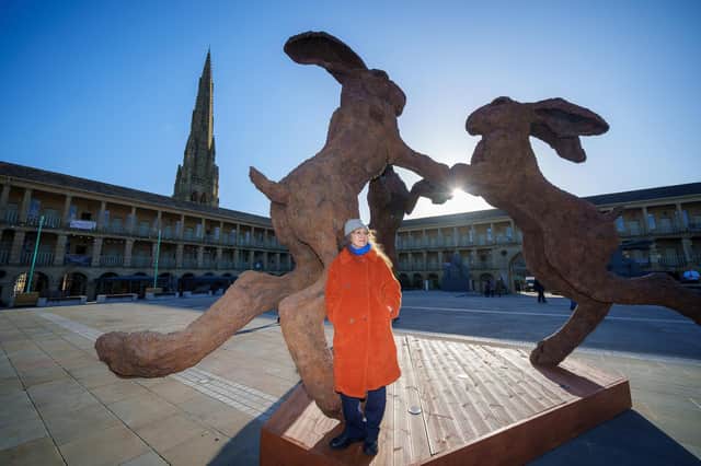British sculptor Sophie Ryder poses next to her work â€ ̃Dancing Haresâ€TM, in the courtyard of the historic Piece Hall on February 10, 2022 in Halifax. The sculptures are on display until May 23. Photo by Christopher Furlong/Getty Images.