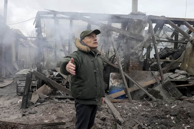 A man opens his arms as he stands near a house destroyed in the Russian artillery shelling, in the village of Horenka close to Kyiv, Ukraine, Sunday, March 6, 2022. On Day 11 of Russia's war on Ukraine, Russian troops shelled encircled cities, and it appeared that a second attempt to evacuate civilians from the besieged port city of Mariupol had failed due to continued violence. (AP Photo/Efrem Lukatsky)