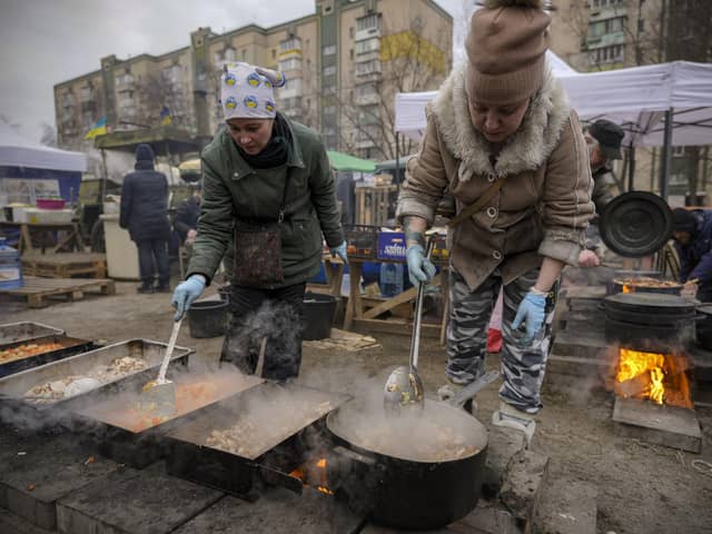 People cook outdoors for Ukrainian servicemen and civil defense members serving in Kyiv, Ukraine, Monday, March 7, 2022. The United Nations is unable to meet the needs of millions of civilians caught in conflict in Ukraine today and is urging safe passage for people to go "in the direction they choose" and for humanitarian supplies to get to areas of hostilities, according to the U.N. humanitarian chief. (AP Photo/Vadim Ghirda).